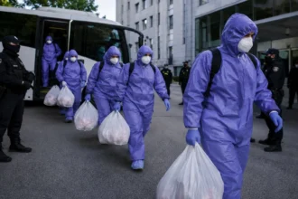 People in hazmat suits disembarking bus
