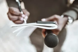 صورة تعبيرية لصحفي في الميدان يحمل دفتراً و ميكروفوناً